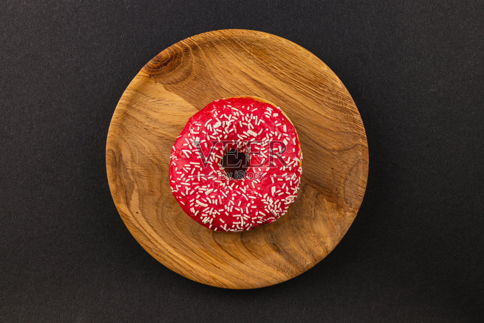 新鲜美味的红色糖霜甜甜圈放在木盘上，俯视图照片摄影图片