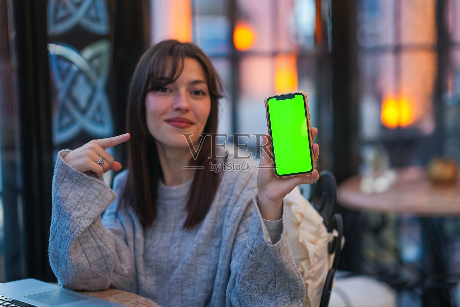 女性指着带有绿色屏幕的手机，移动应用推广活动照片摄影图片