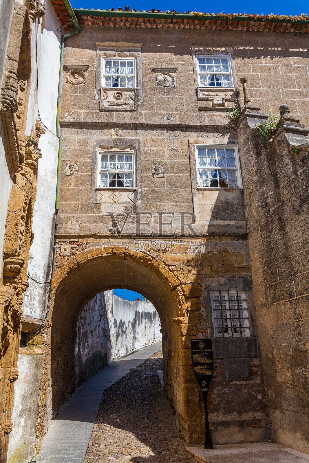 一条狭窄的鹅卵石街道，两旁是历史悠久的建筑，拥有精美的石雕和宏伟的拱形门道照片摄影图片