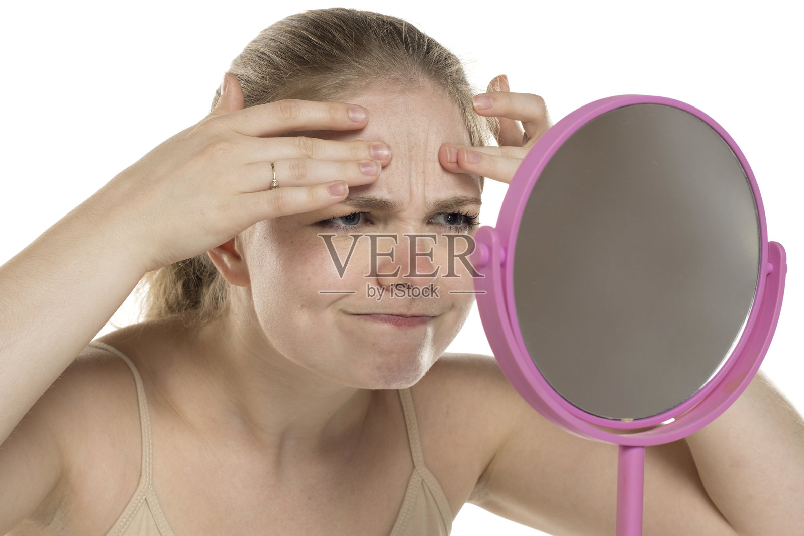 年轻的金发女性担心地检查额头上的皱纹。照片摄影图片