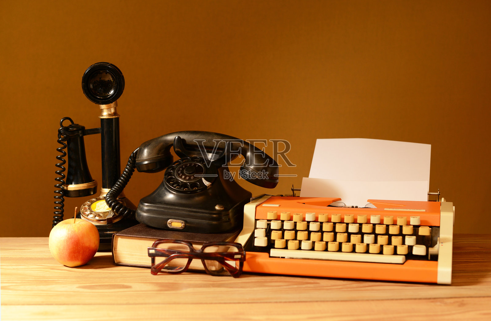 静物，两个旧电话，一台打字机，一个苹果，一本书放在木桌上照片摄影图片