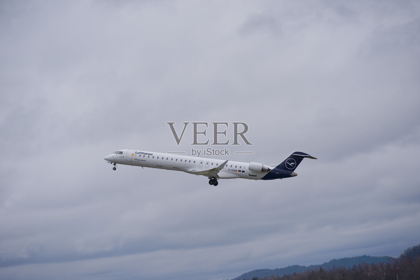 侧面视角的汉莎航空客机庞巴迪CRJ-900,注册号D-ACNW,在多云的秋日下午从苏黎世机场起飞。照片摄影图片