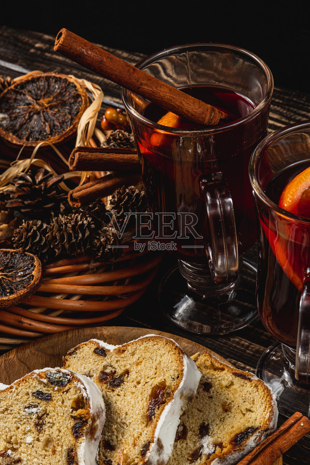 两杯香料热红酒，盘子上放着圣诞果仁蛋糕，摆放在木桌上照片摄影图片
