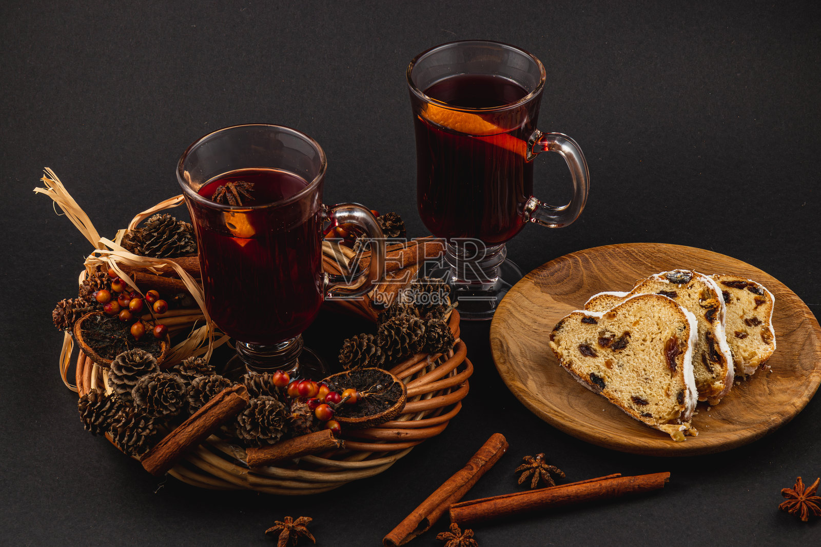 香料热红酒与新鲜的斯托伦蛋糕放在黑色背景的木盘上照片摄影图片