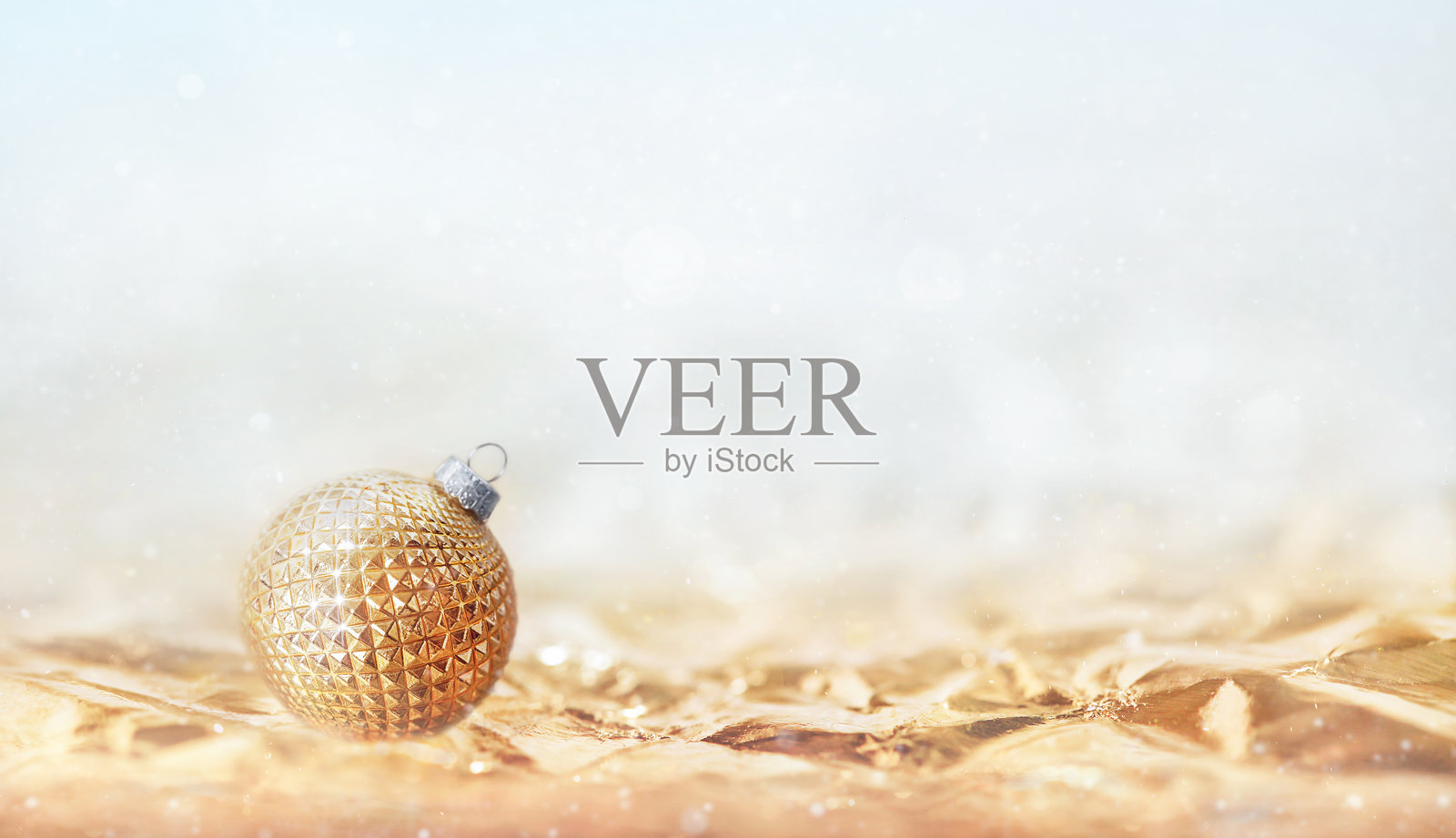 一个金色的圣诞球，带有几何图案，背景是柔和的散景，留有空白空间。照片摄影图片