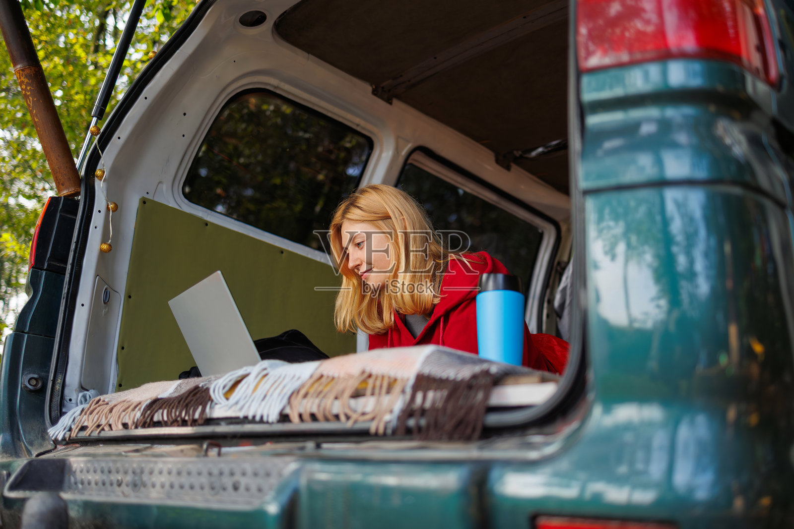 女孩在大自然中放松时，直接从面包车上使用笔记本电脑工作照片摄影图片