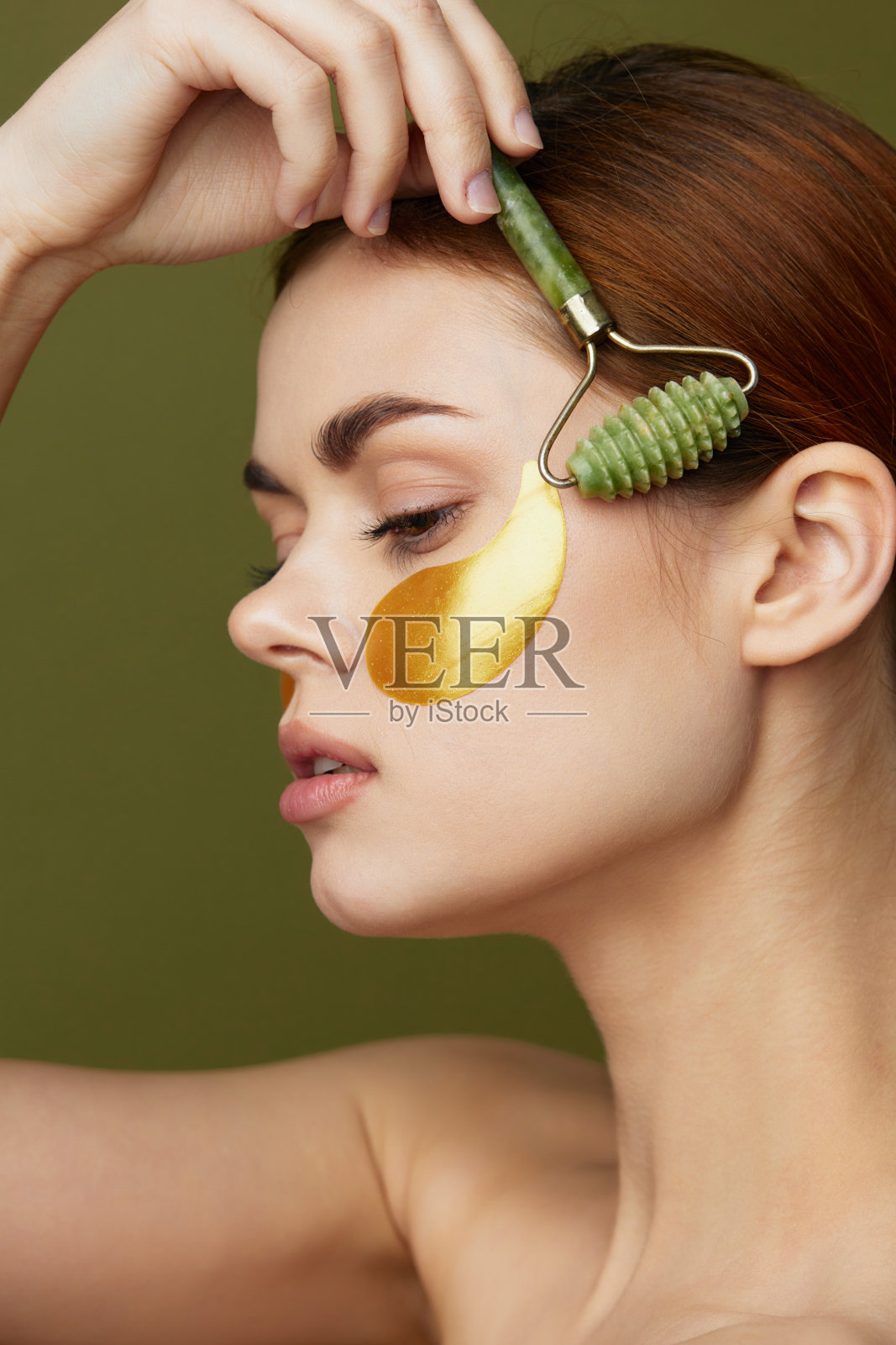 裸肩女性使用护肤面膜，背景纯色，注重个人卫生。照片摄影图片