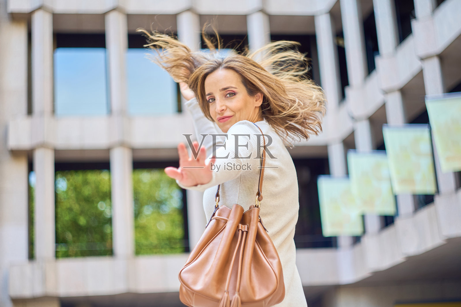 户外一位女性挥手，头发随风飘动照片摄影图片
