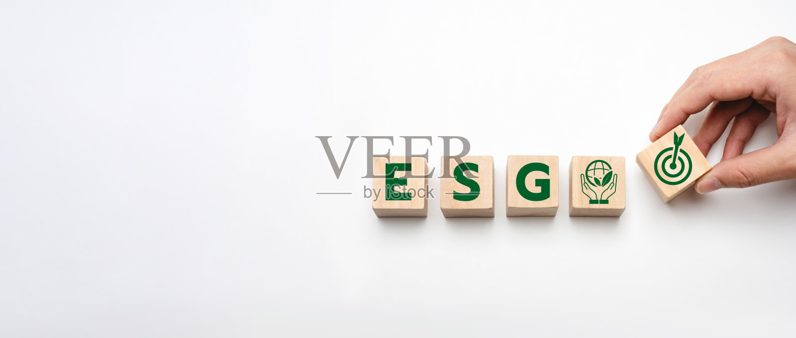 代表ESG原则的木块 - 环境、社会和治理图标，手添加目标符号，强调企业责任、可持续性和道德实践照片摄影图片