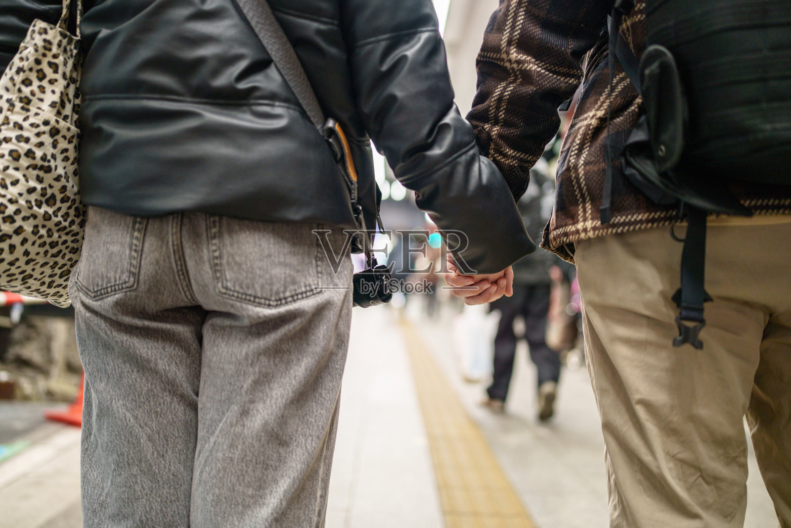 街头一对情侣手牵手的特写镜头。照片摄影图片