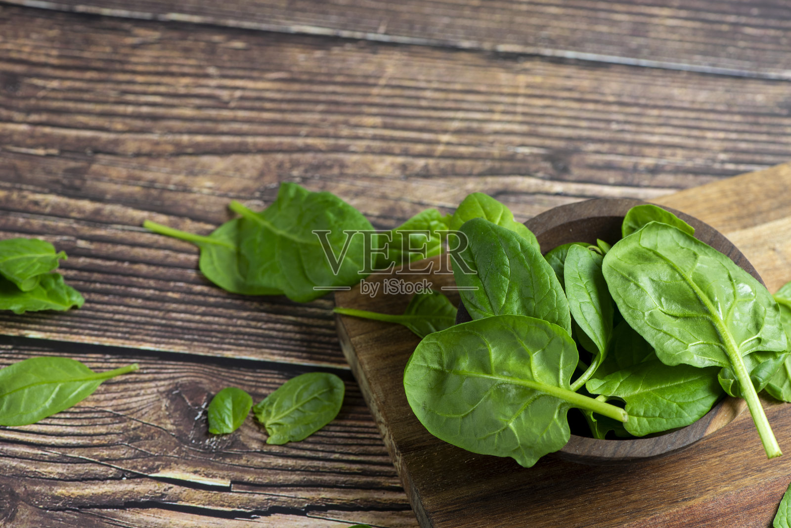 木质背景上的小碗里装着菠菜照片摄影图片