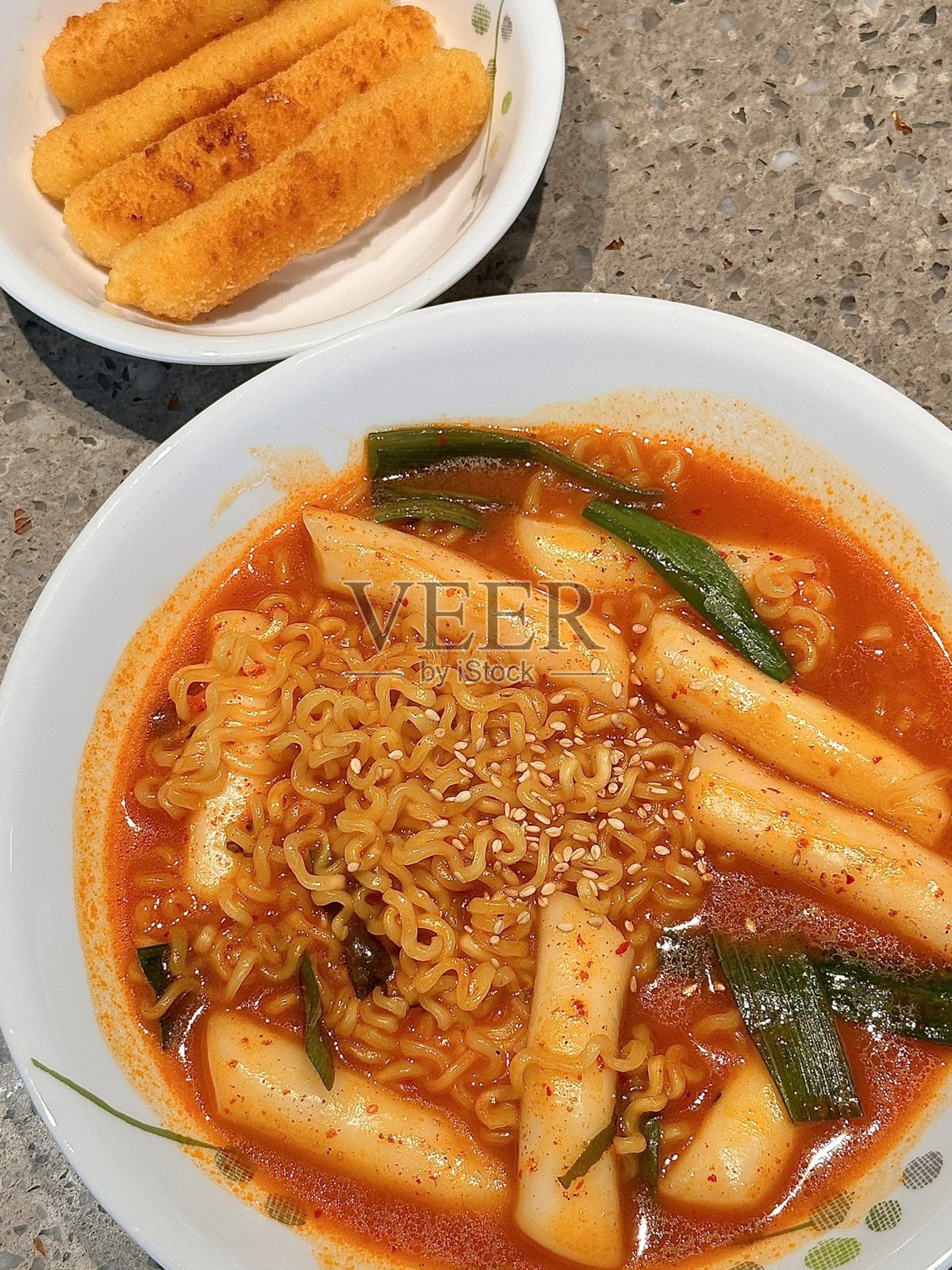 Rabokki将韩国拉面与有嚼劲的年糕（米糕）结合在一起，配以辛辣甜美的辣椒酱。通常加入鱼饼、蔬菜和煮鸡蛋，这种受欢迎的韩国街头食品是一道舒适、味道丰富的菜肴，完美融合了各种风味。照片摄影图片