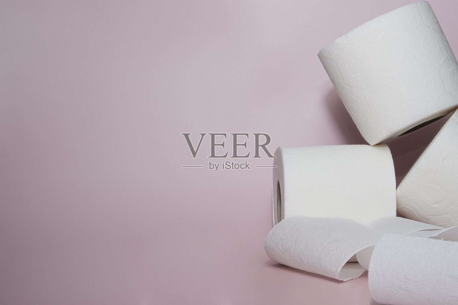 创意排列的卫生纸卷，背景为柔和的粉色。简约的环境突显了卫生、清洁和日常必需品。照片摄影图片