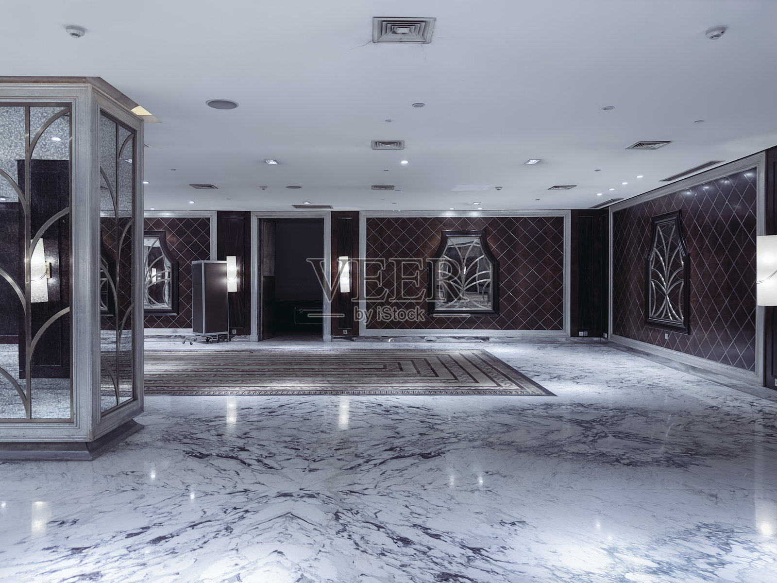 现代优雅的酒店大堂或活动走廊，配有奢华的大理石地板、装饰性镜面面板和艺术装饰风格的图案、柔和的环境照明以及简约的鸡尾酒桌。照片摄影图片
