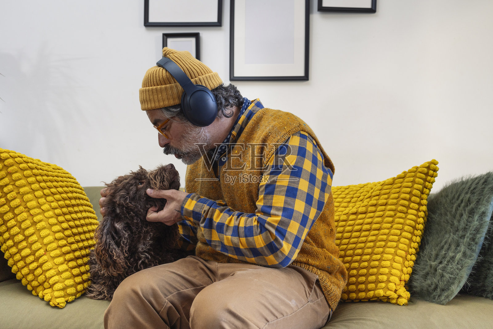 男人坐在沙发上抚摸和玩耍狗狗照片摄影图片