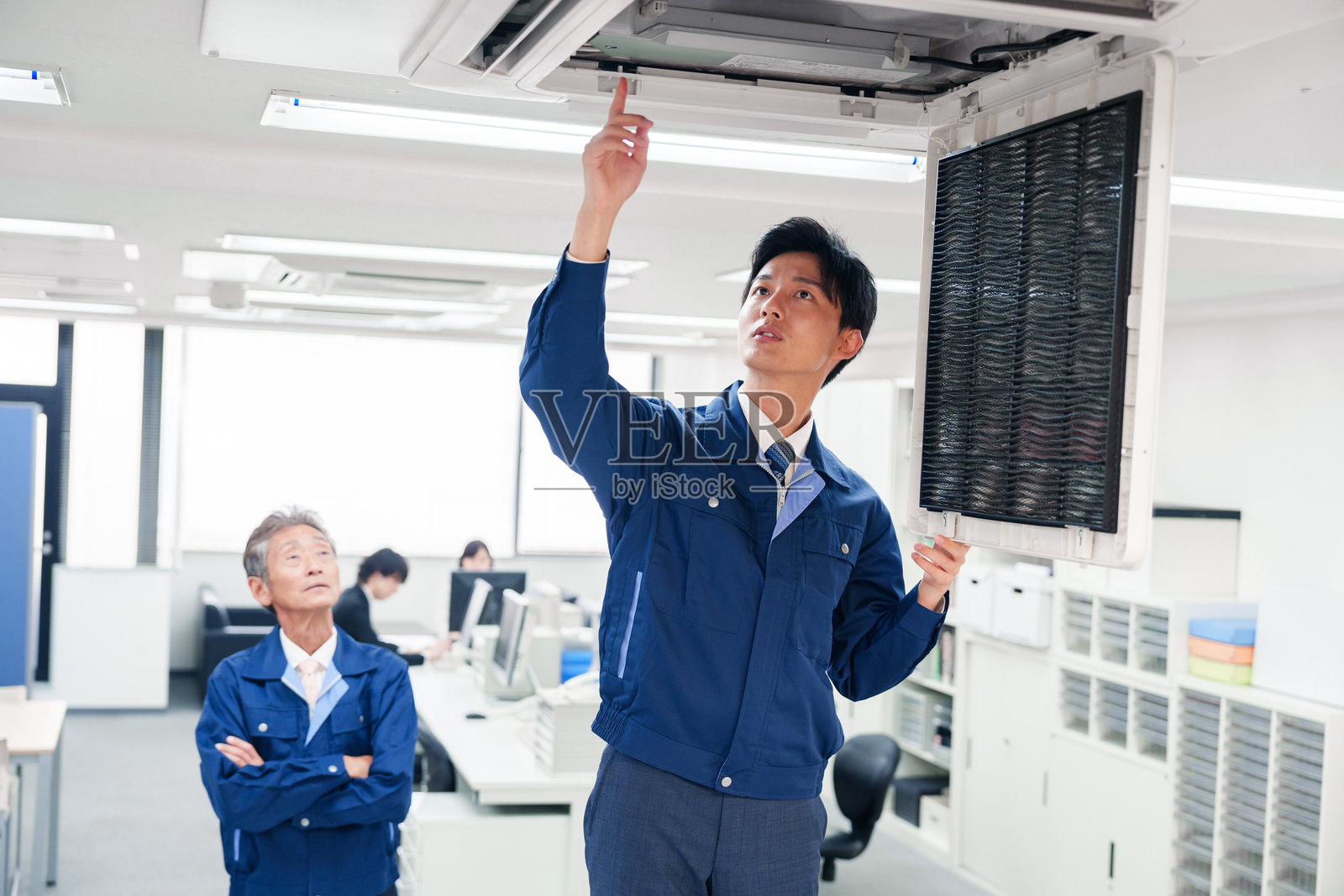 穿着工作服的男子正在检查建筑物的空调照片摄影图片