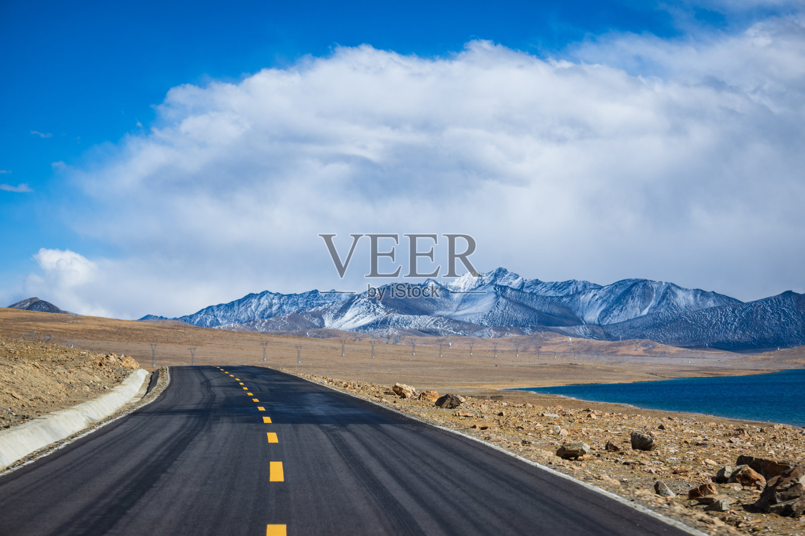 雪山脚下无尽的沥青道路照片摄影图片