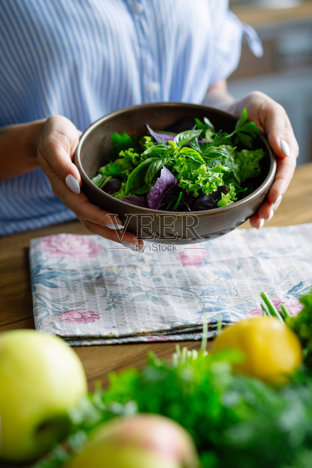 特写镜头：一位女性的手握着一碗绿色沙拉，营养丰富的混合菜。照片摄影图片