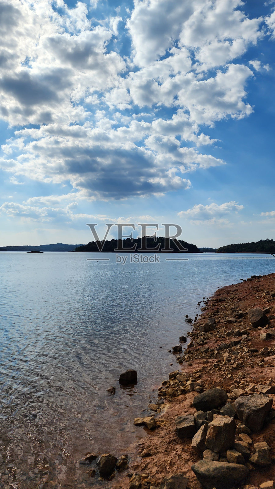 宁静的湖边景色，岩石海岸在部分多云的天空下照片摄影图片
