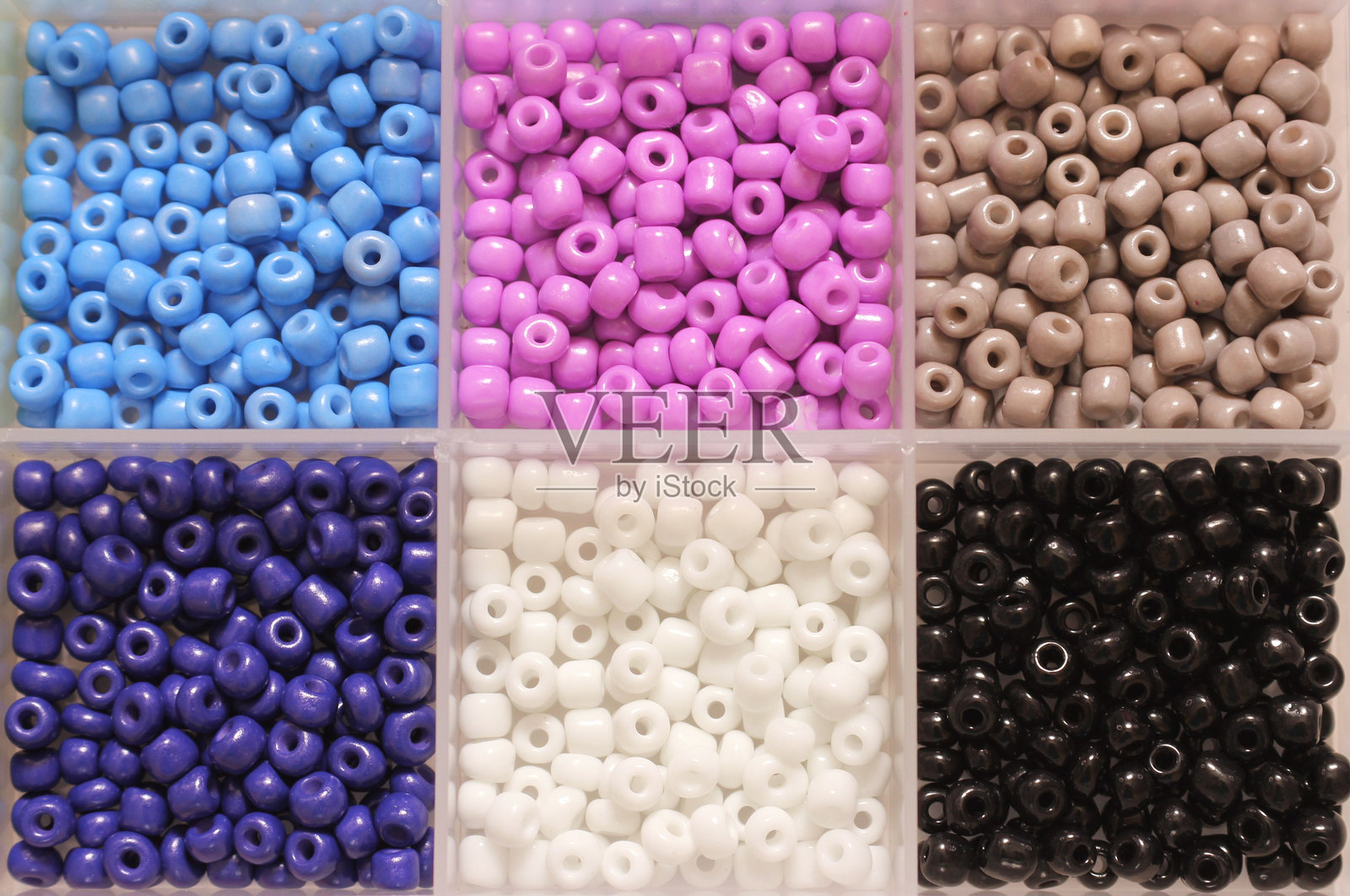 有序的彩色珠子放在隔间里。照片摄影图片