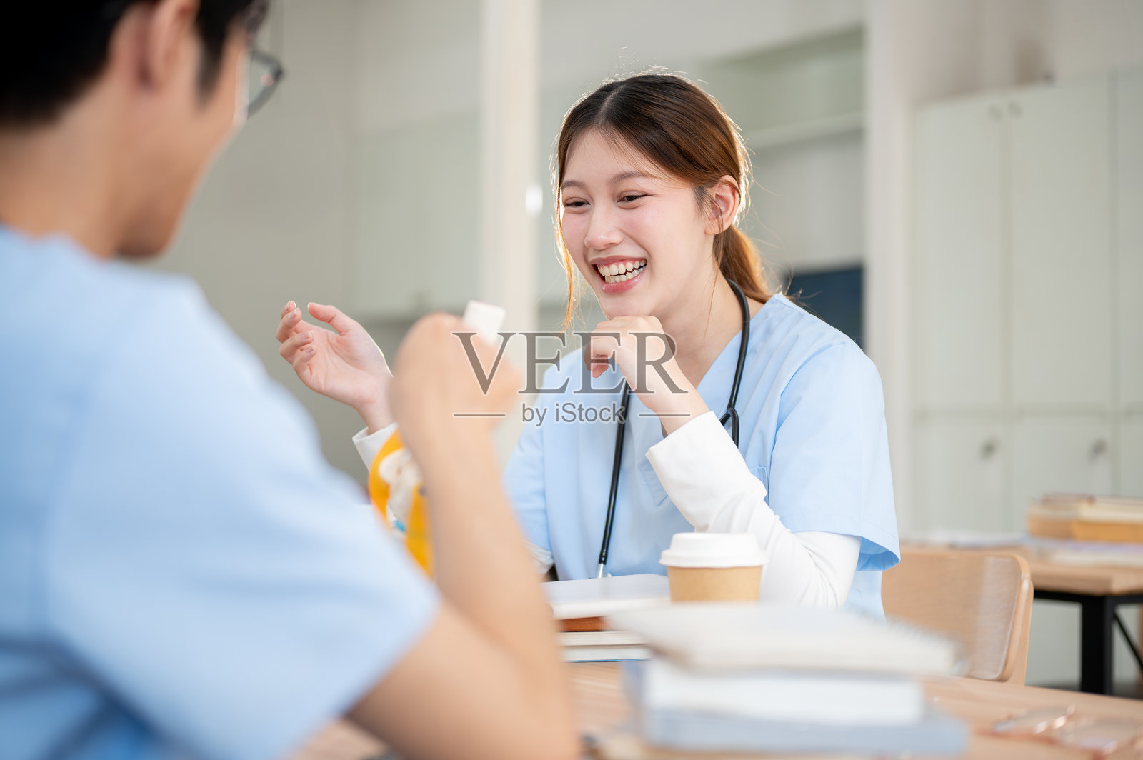 一位积极向上的亚洲女性医学生正在图书馆与她的男性同学一起学习。照片摄影图片