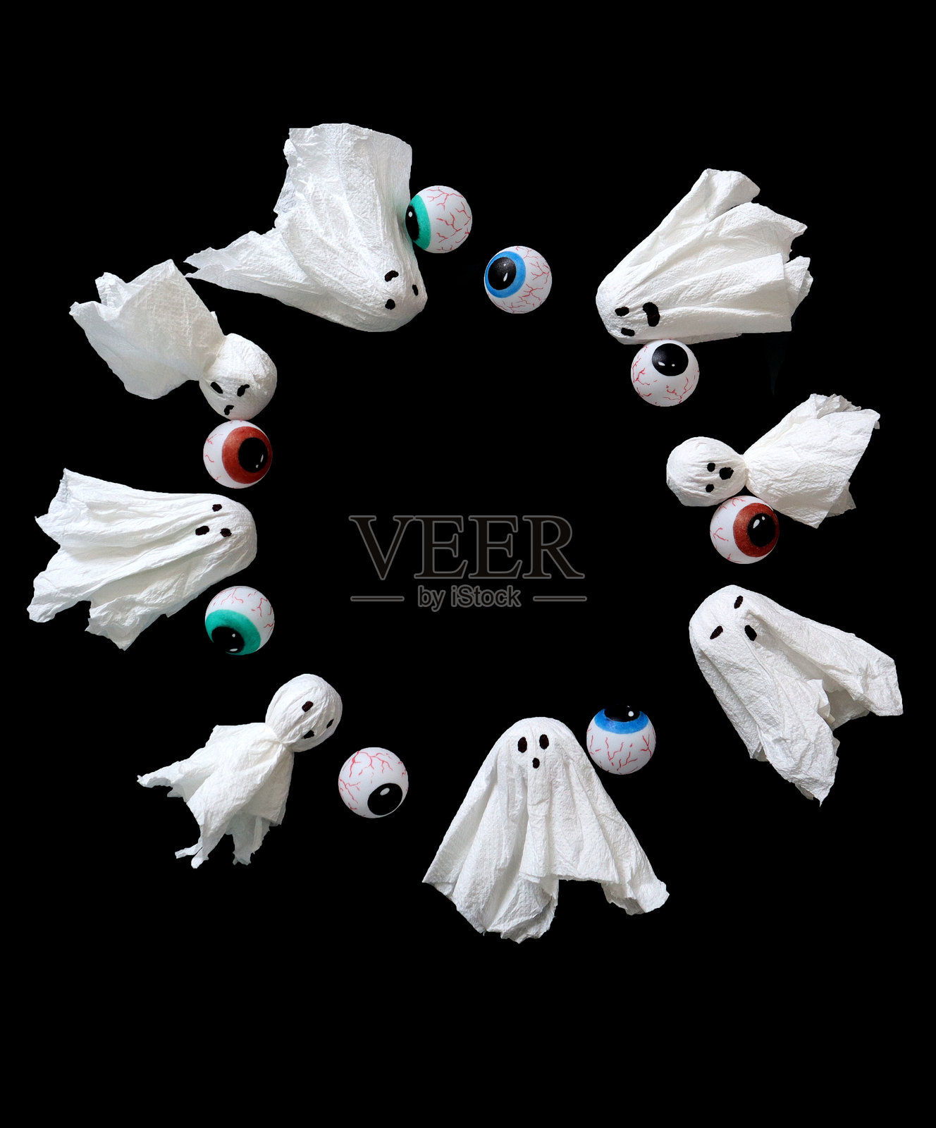 圆形框架内有手工制作的鬼魂和眼睛。黑色背景。万圣节。照片摄影图片