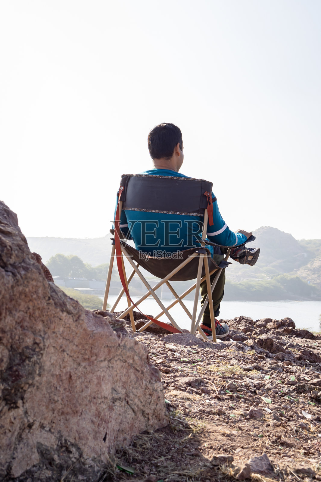 男人在露营椅上放松，享受日出时的湖景照片摄影图片