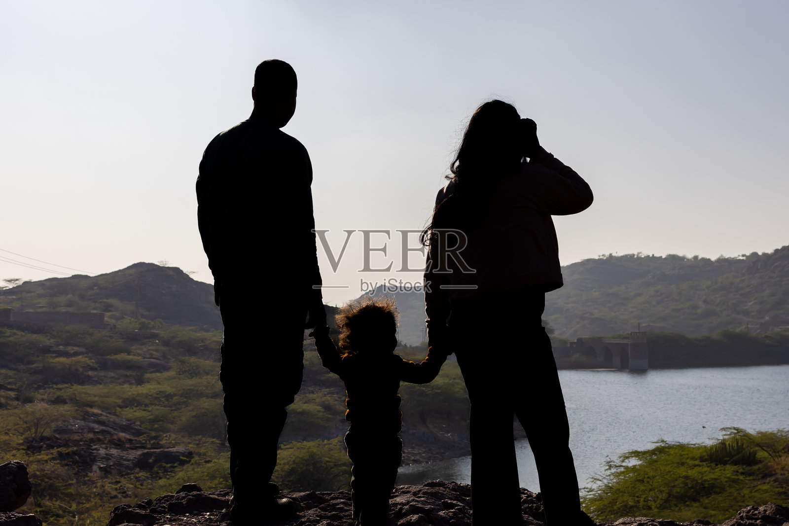 年轻父母与幼儿在宁静的山顶晨光中亲密互动照片摄影图片