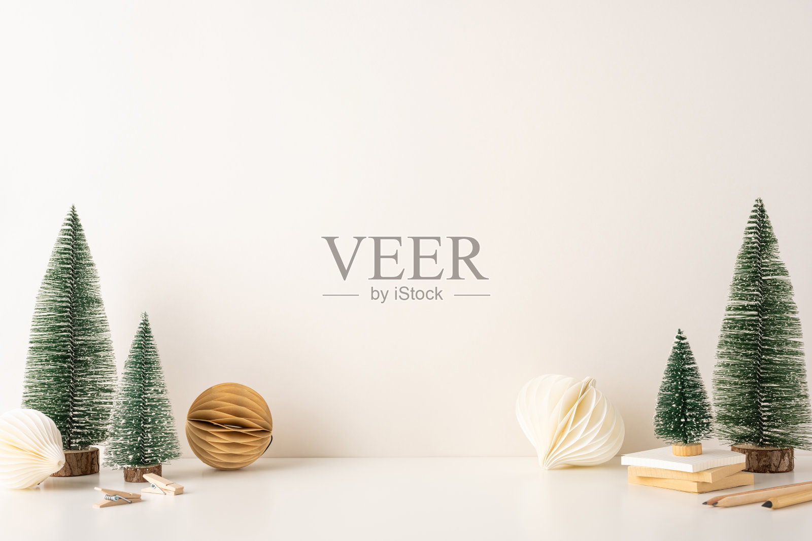 极简主义侧视斯堪的纳维亚冬季装饰，包含小型圣诞树和纸质装饰品。干净简约的设计营造出温馨优雅的氛围，非常适合节日季节。照片摄影图片