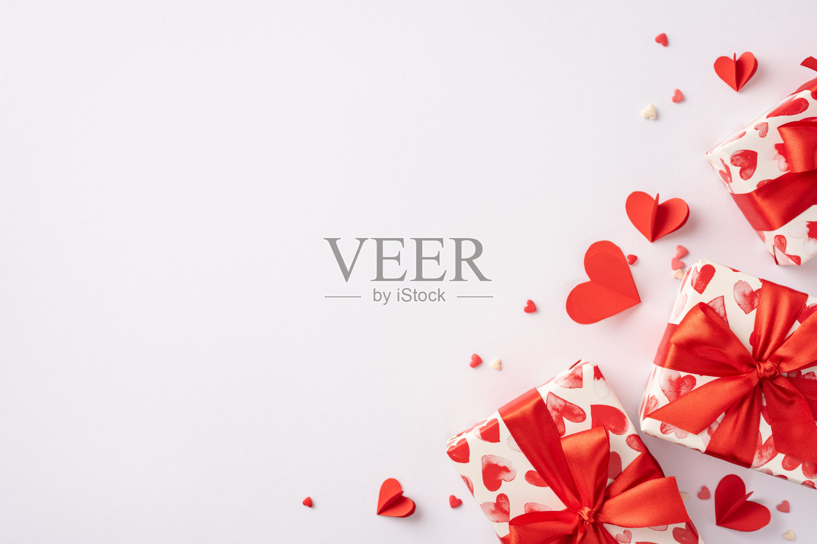 情人节礼物上装饰着红色心形图案和丝带，背景为白色，营造出节日的温馨氛围。照片摄影图片