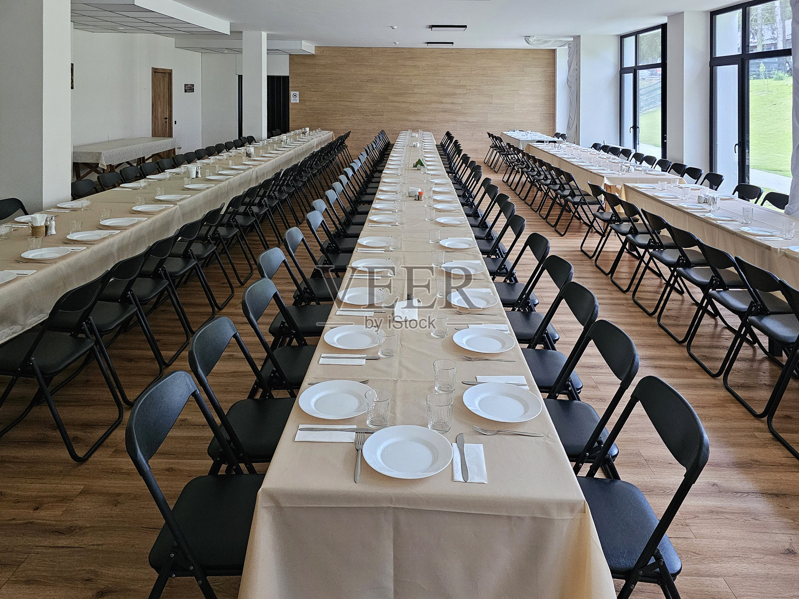 大型餐厅内摆放的长桌，桌上有餐具。没有客人的婚礼桌。用于重要活动的大型宴会厅。照片摄影图片