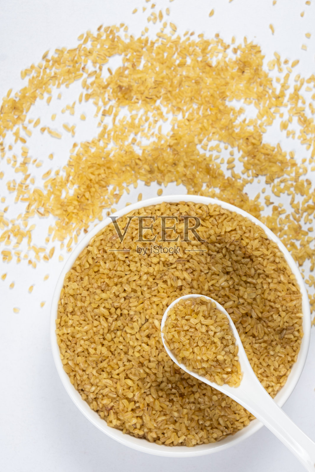 未煮的粗麦粉在勺子和盘子上的俯视图照片摄影图片