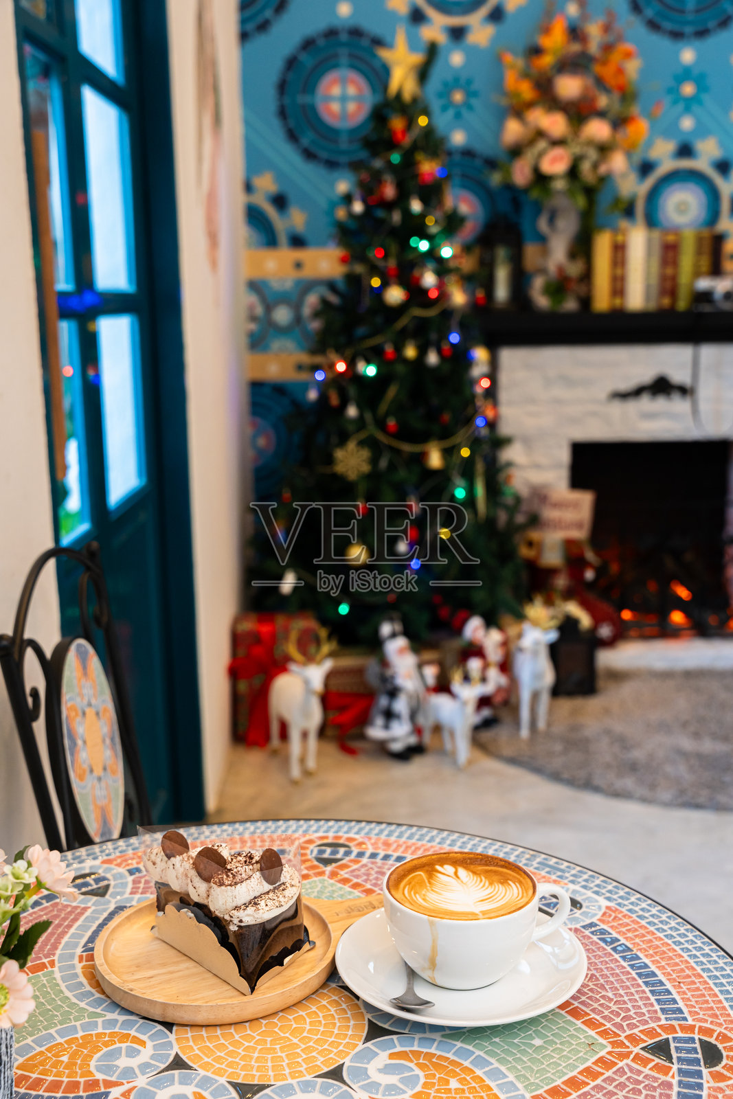 圣诞快乐，热咖啡拿铁杯中盛着拉花奶泡，旁边是装饰有圣诞装饰品的自制巧克力蛋糕和圣诞树球，摆放在大理石桌面上，庆祝圣诞节和新年。照片摄影图片