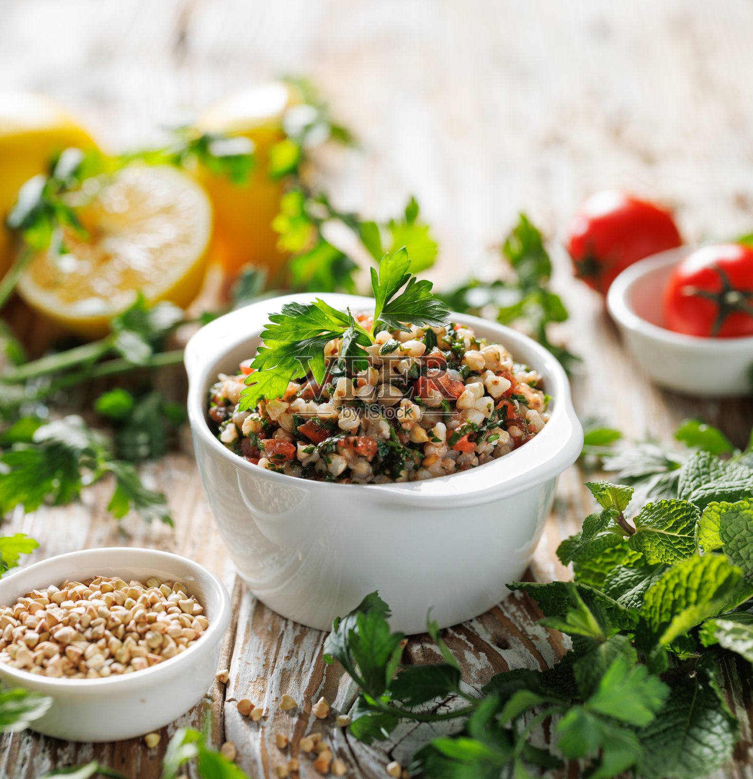 绿色荞麦粒沙拉，配有新鲜香草、西红柿、柠檬汁和橄榄油，盛放在陶瓷碗中，特写视图。照片摄影图片