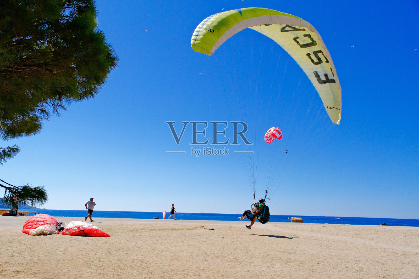 游客在费特希耶的沙滩上即将降落的滑翔伞运动照片摄影图片