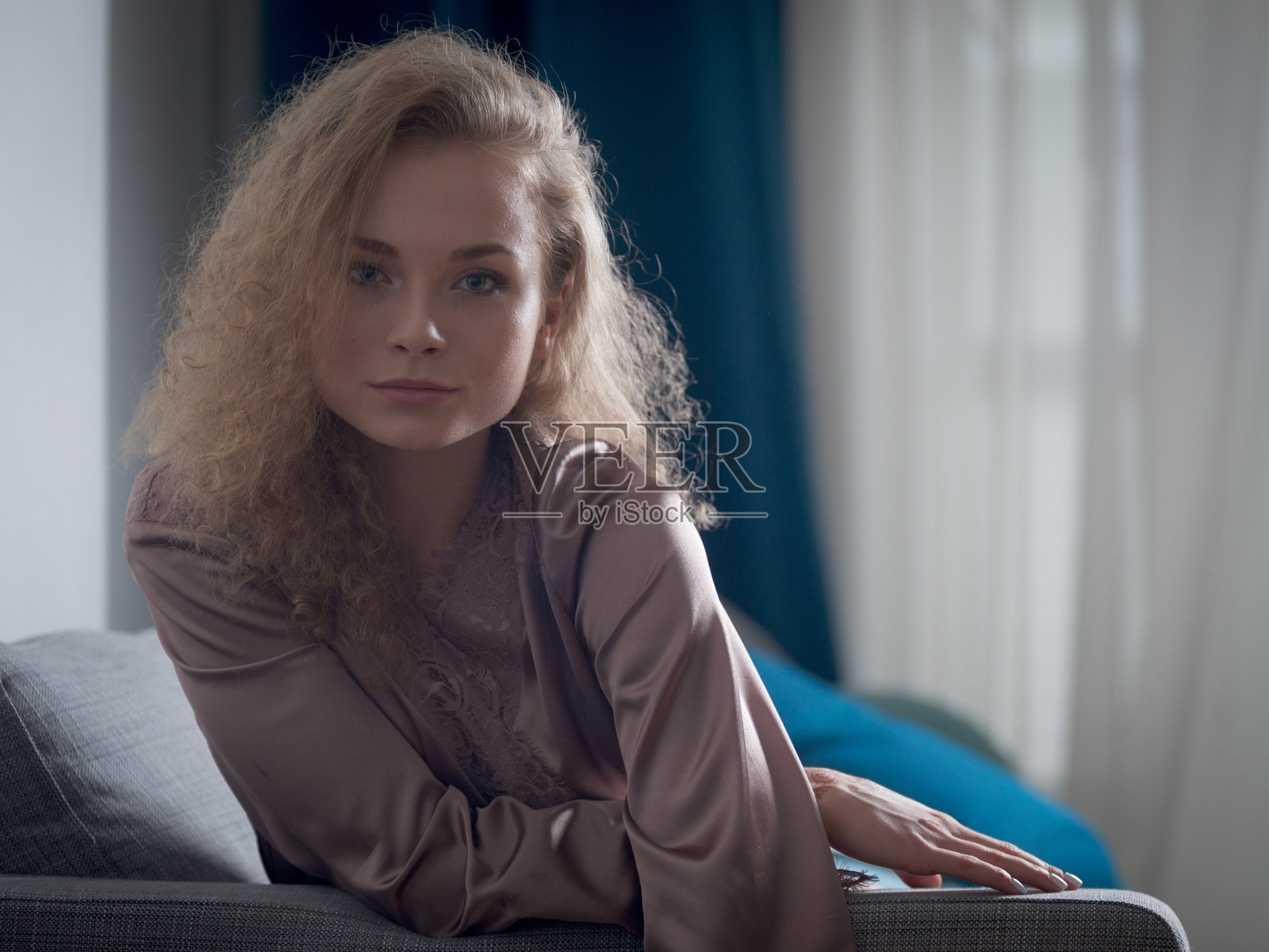 年轻迷人的女性舒适地坐在沙发上微笑。照片摄影图片