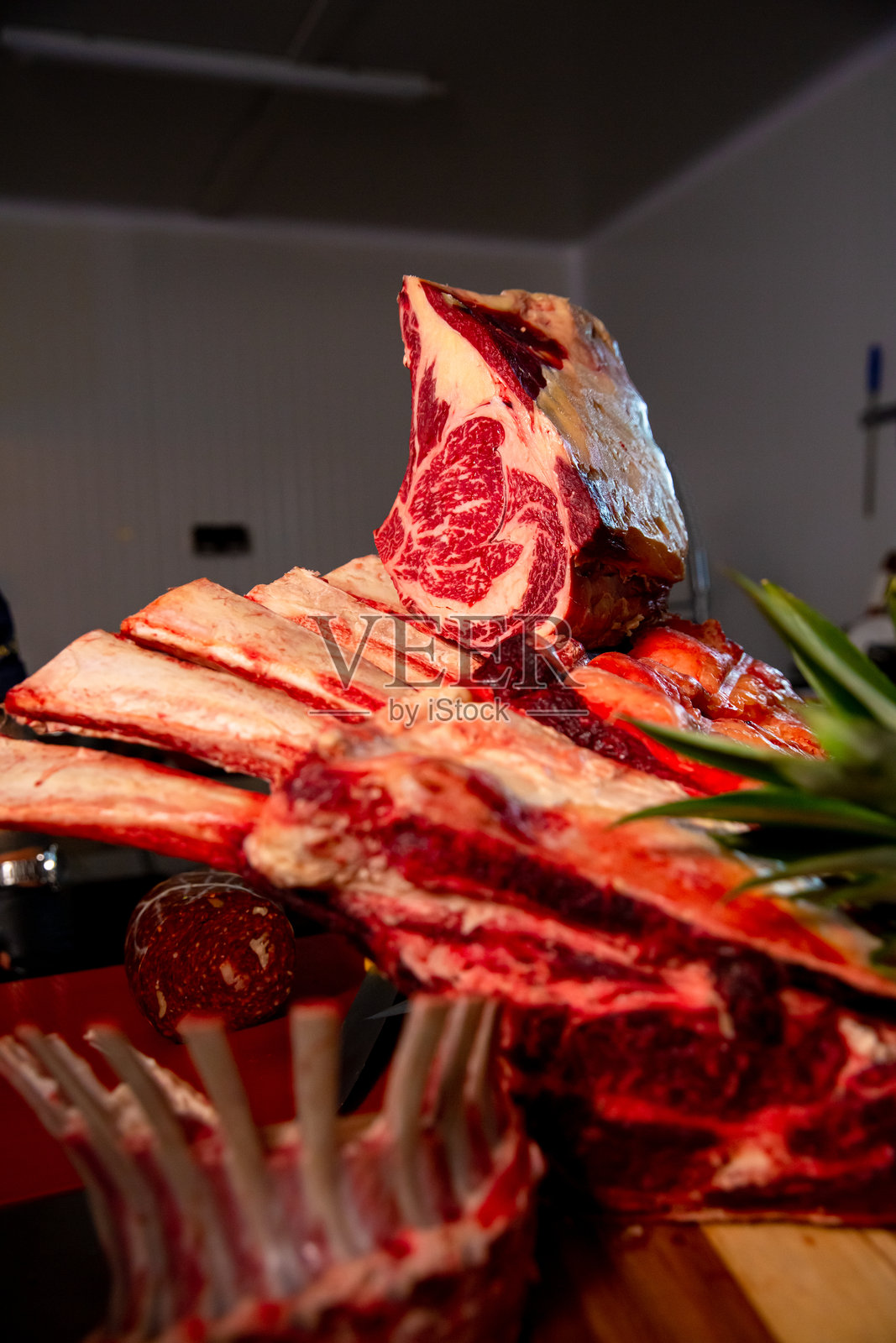 肉类商品在肉铺厨房的装饰性陈列。多种生肉和调味肉类商品摆放在木板和金属桌上。照片摄影图片