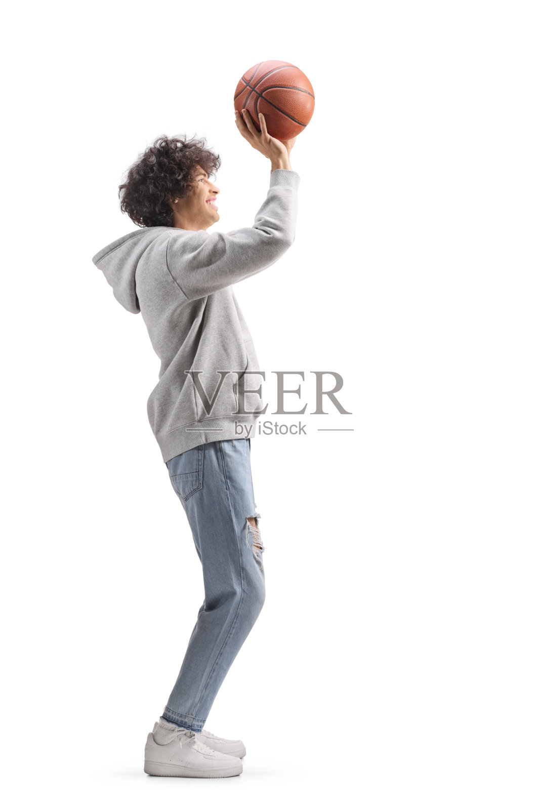 年轻男子穿着牛仔裤和连帽衫打篮球的全身侧面照照片摄影图片