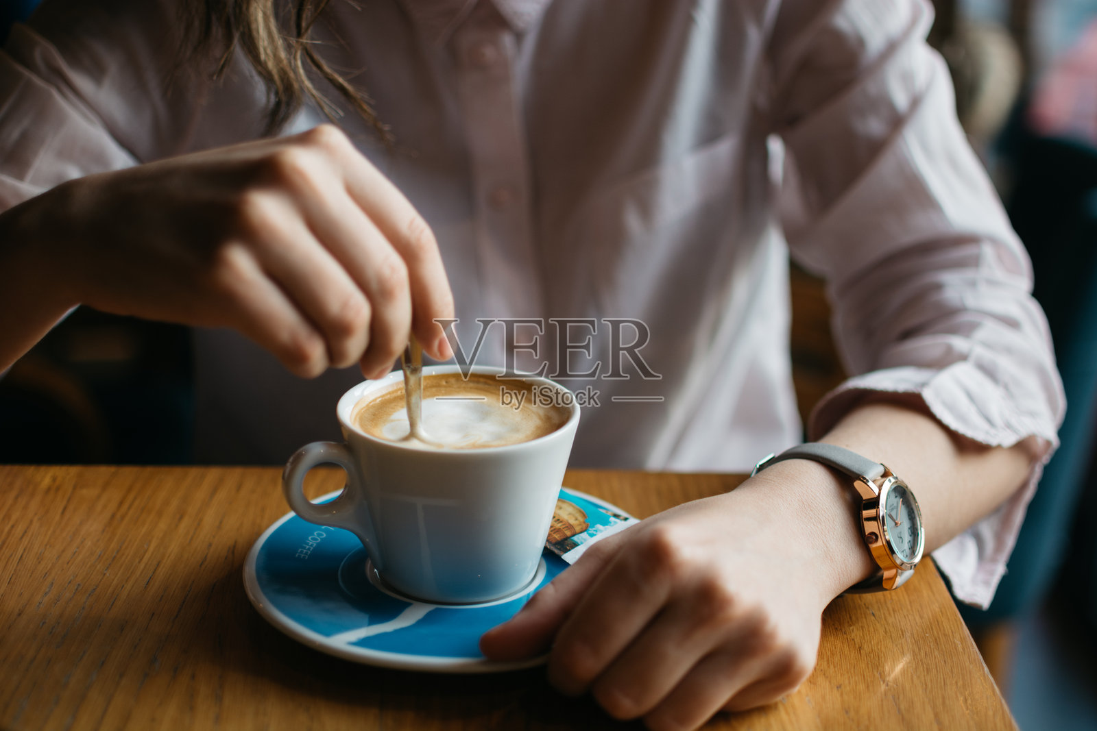 坐在咖啡馆里的女人中部，桌上放着咖啡杯照片摄影图片
