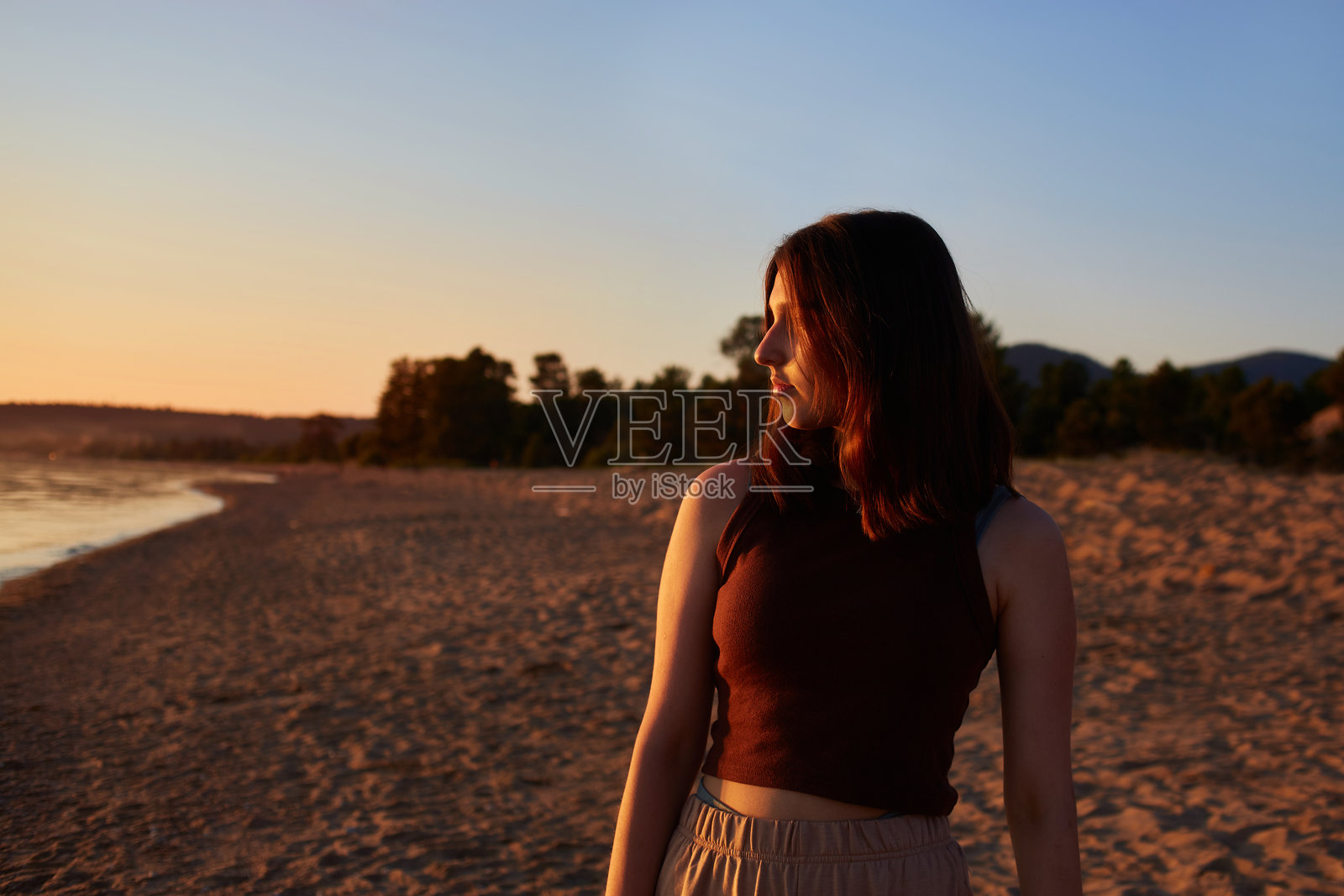 一个女孩在沙滩上享受日落。夏季旅行，海边假期。照片摄影图片