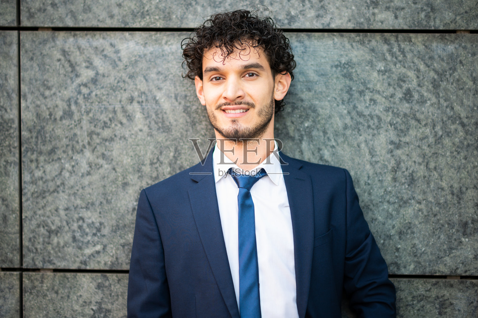 微笑的年轻商人靠在墙上拍摄的肖像照片摄影图片