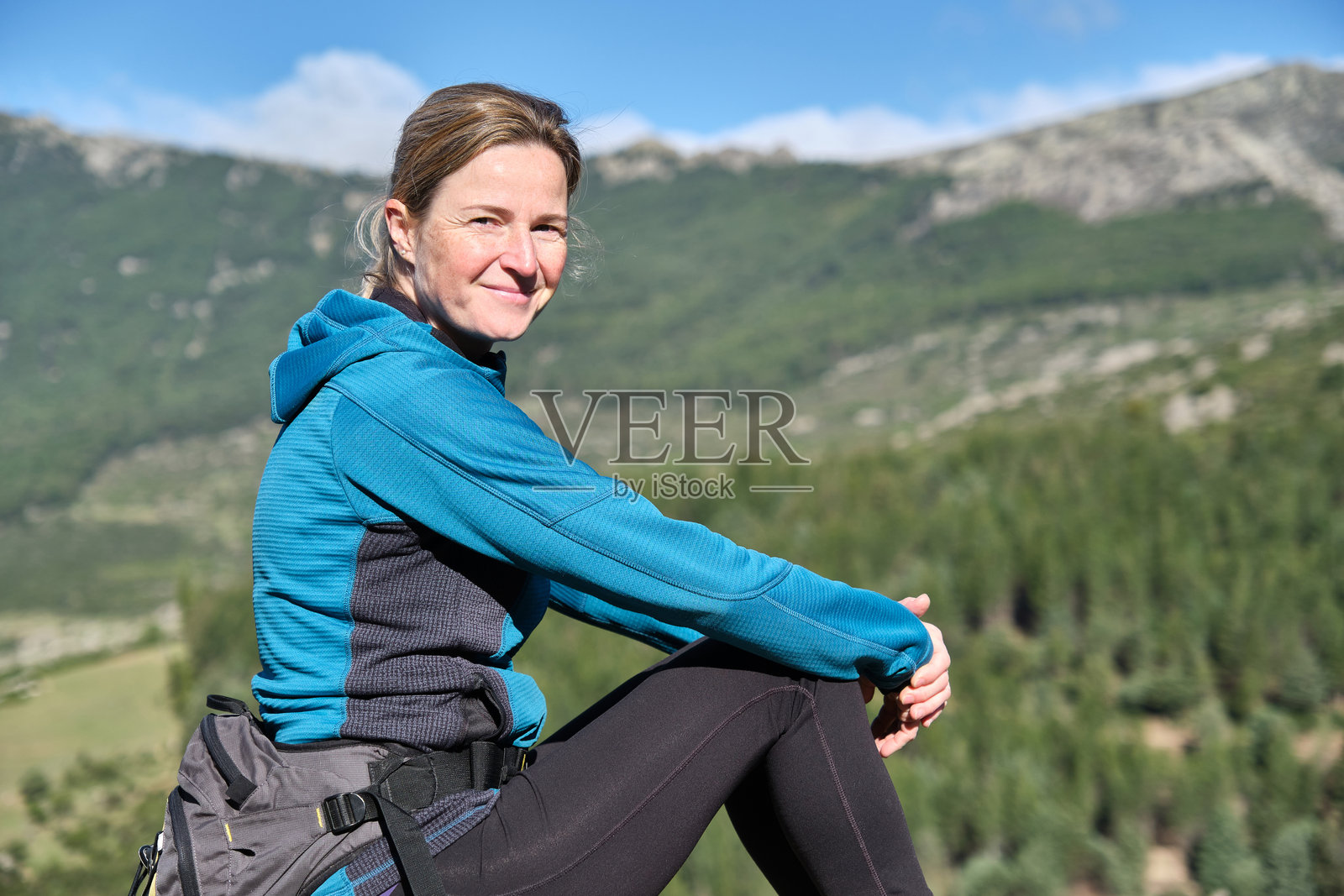 坐在山上的女人肖像，正看着镜头。照片摄影图片