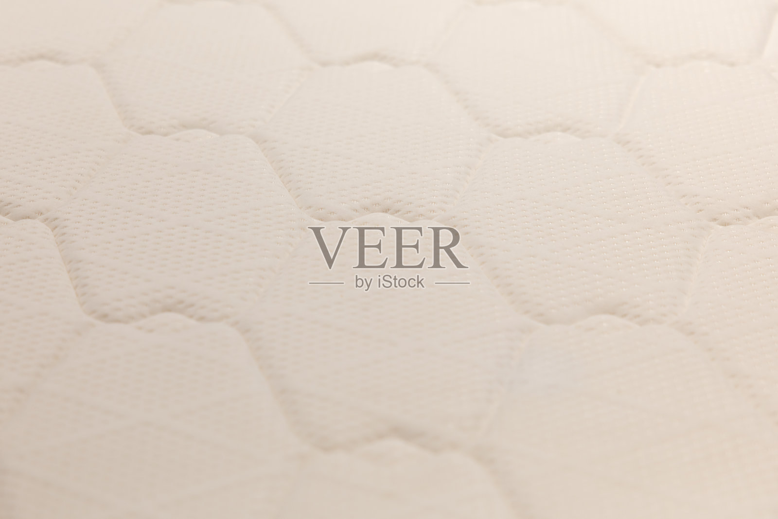 白色床单特写，上面有三角形图案，背景为床垫纹理。照片摄影图片