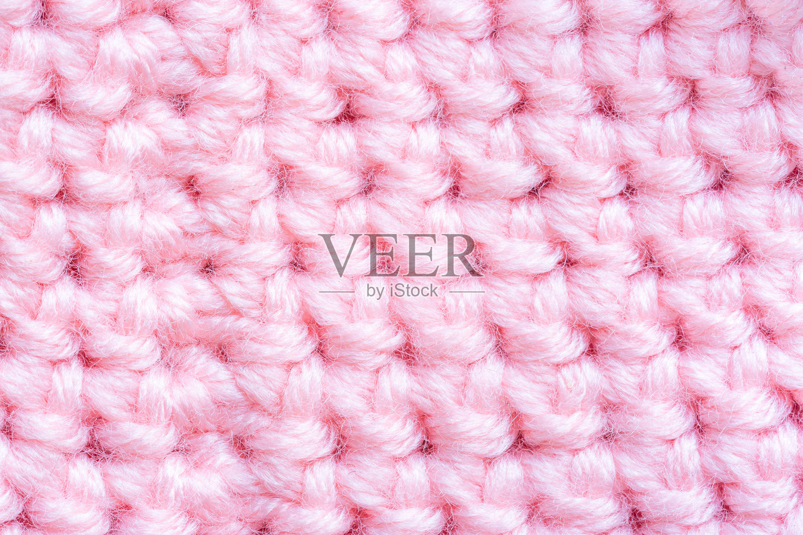 粉色针织毛衣的特写，蔓越莓粉色针织面料的反面特写作为背景。照片摄影图片