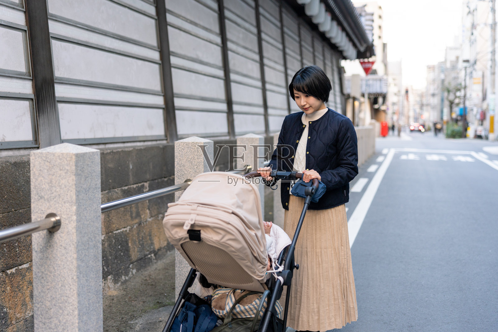 女人在街上走时看着她的婴儿推车里的宝宝照片摄影图片