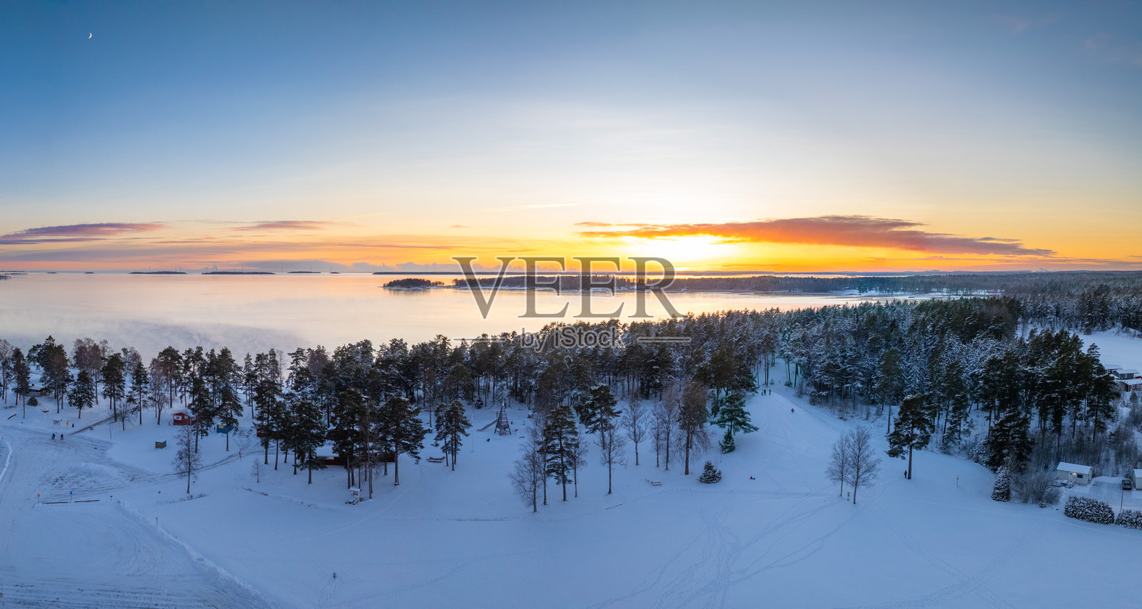 宁静的雪景，夕阳映照在斯堪的纳维亚森林和湖泊上照片摄影图片