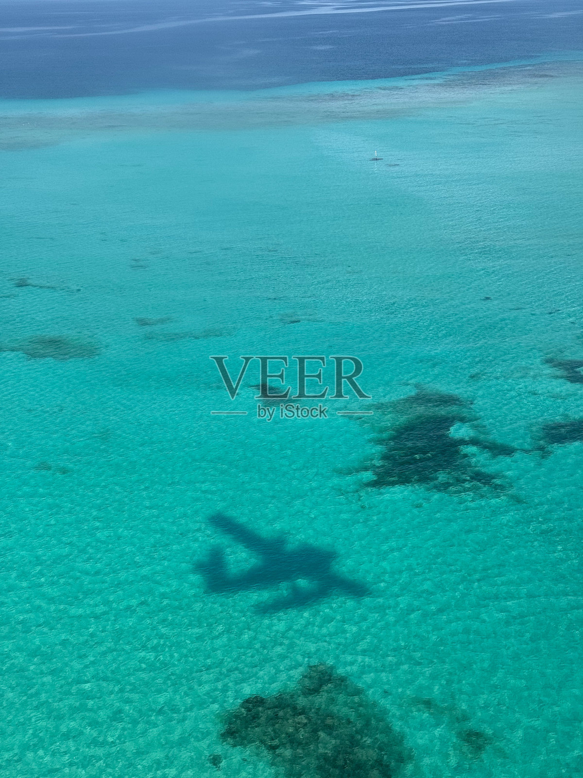 从水上飞机俯瞰马尔代夫岛屿环礁，飞机的影子投射在泻湖上照片摄影图片