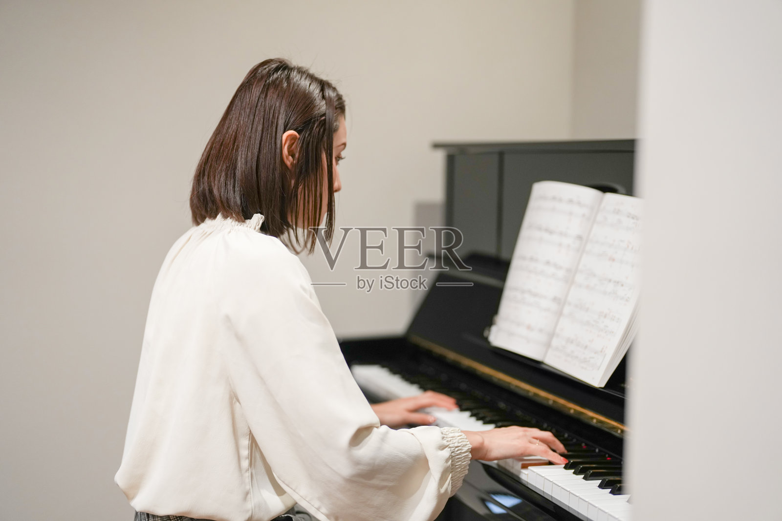 一位30多岁的日本女性在家里弹钢琴。照片摄影图片