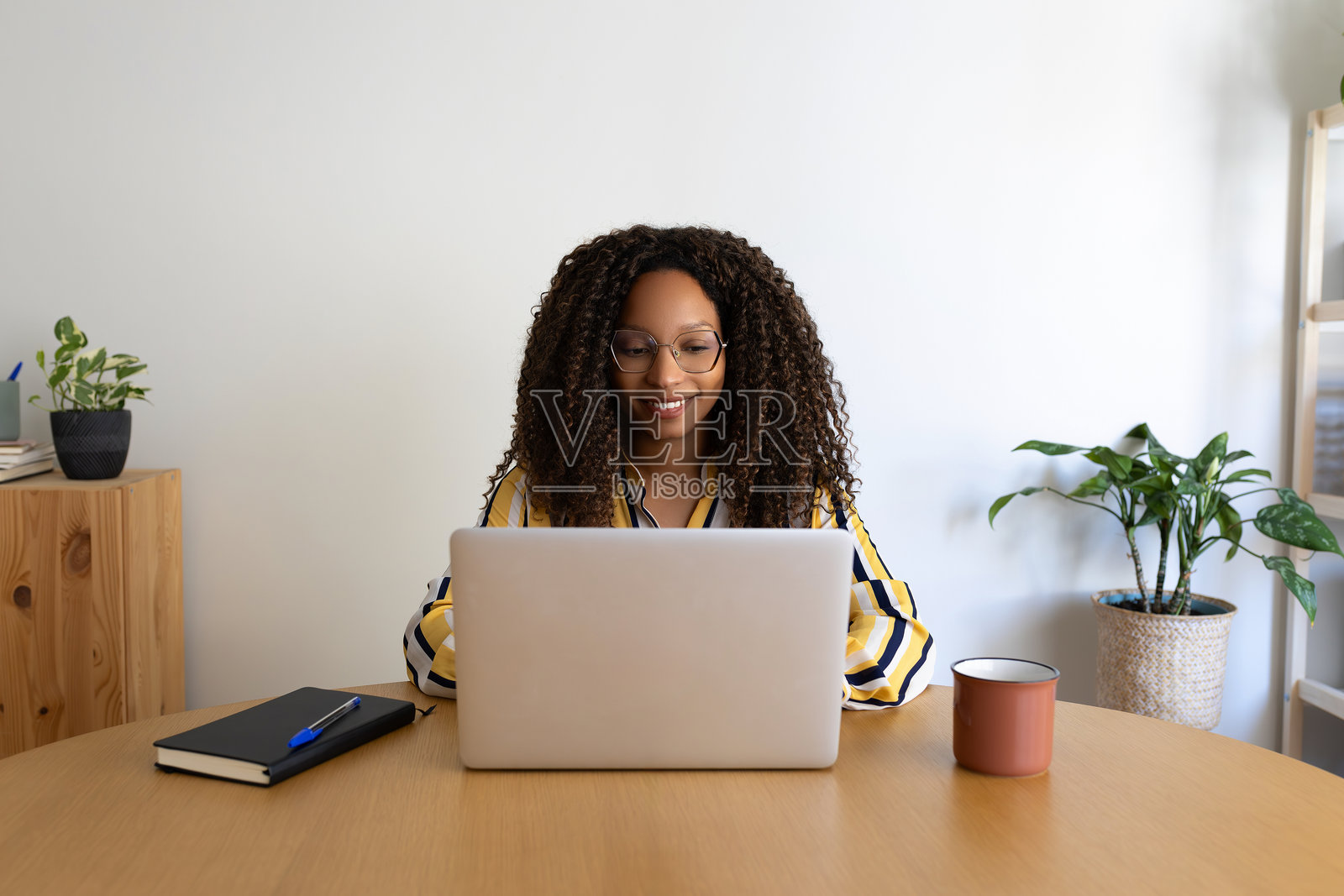 年轻的非裔美国女性在家中办公室工作。快乐的黑人女性企业家使用笔记本电脑。照片摄影图片