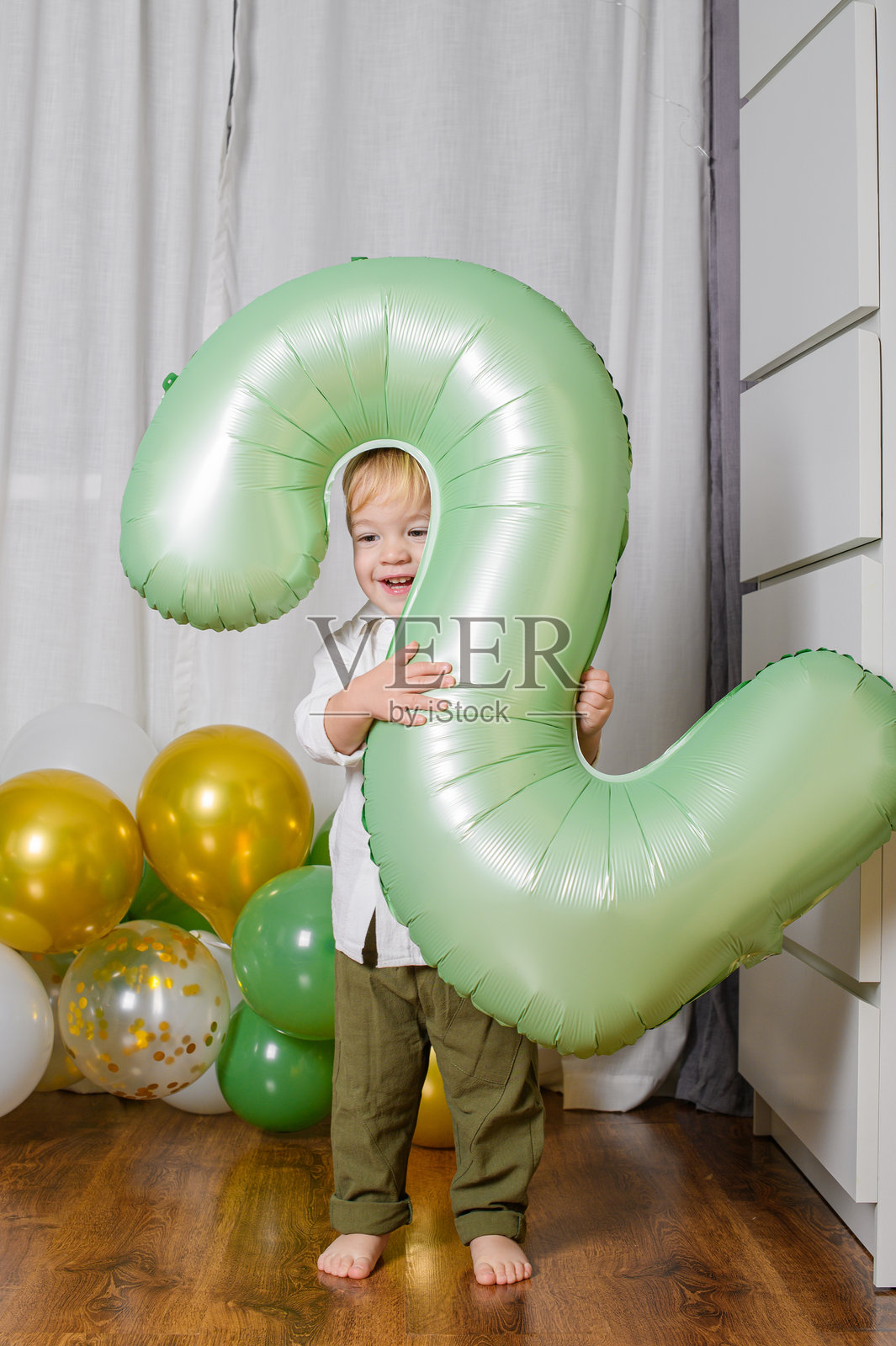 幼儿庆祝二岁生日，手持绿色数字气球照片摄影图片